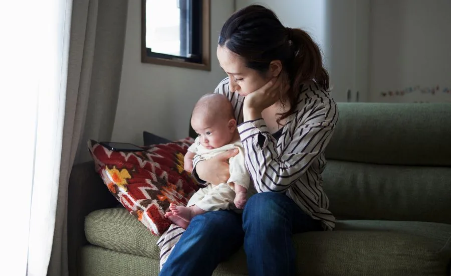子どもを抱きながら育児をする保護者